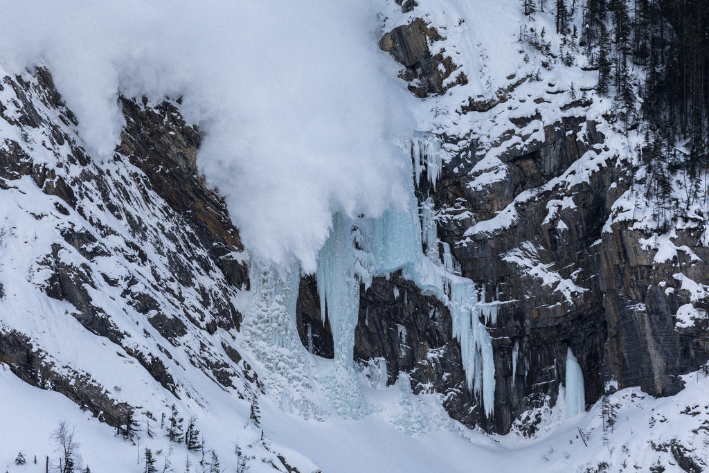 Avalanche descending over Pilsner Pillar ice climbing terrain in the Canadian Rockies