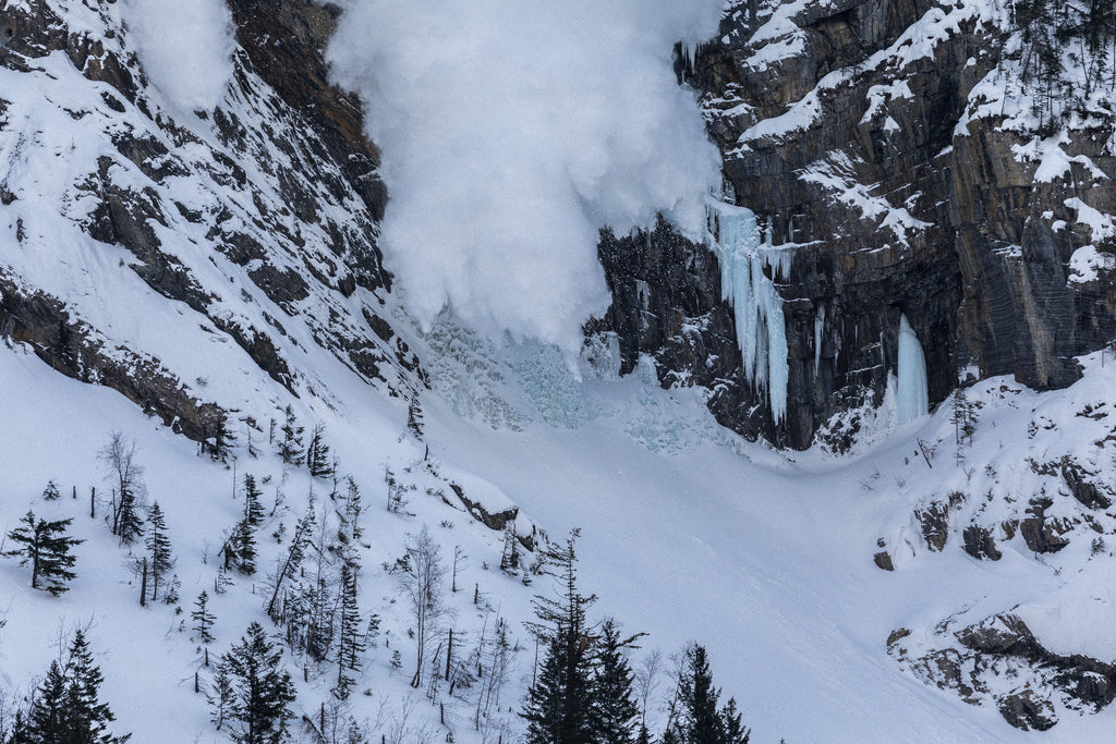 Avalanche descending over Pilsner Pillar ice climbing terrain in the Canadian Rockies