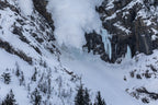 Avalanche descending over Pilsner Pillar ice climbing terrain in the Canadian Rockies
