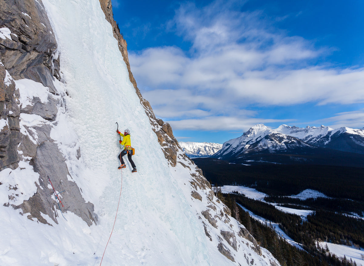Ice climber on Cascade Falls in Banff, with the Canadian Rockies in the background